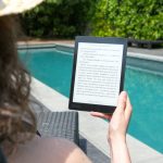 woman sitting beside pool holding tablet